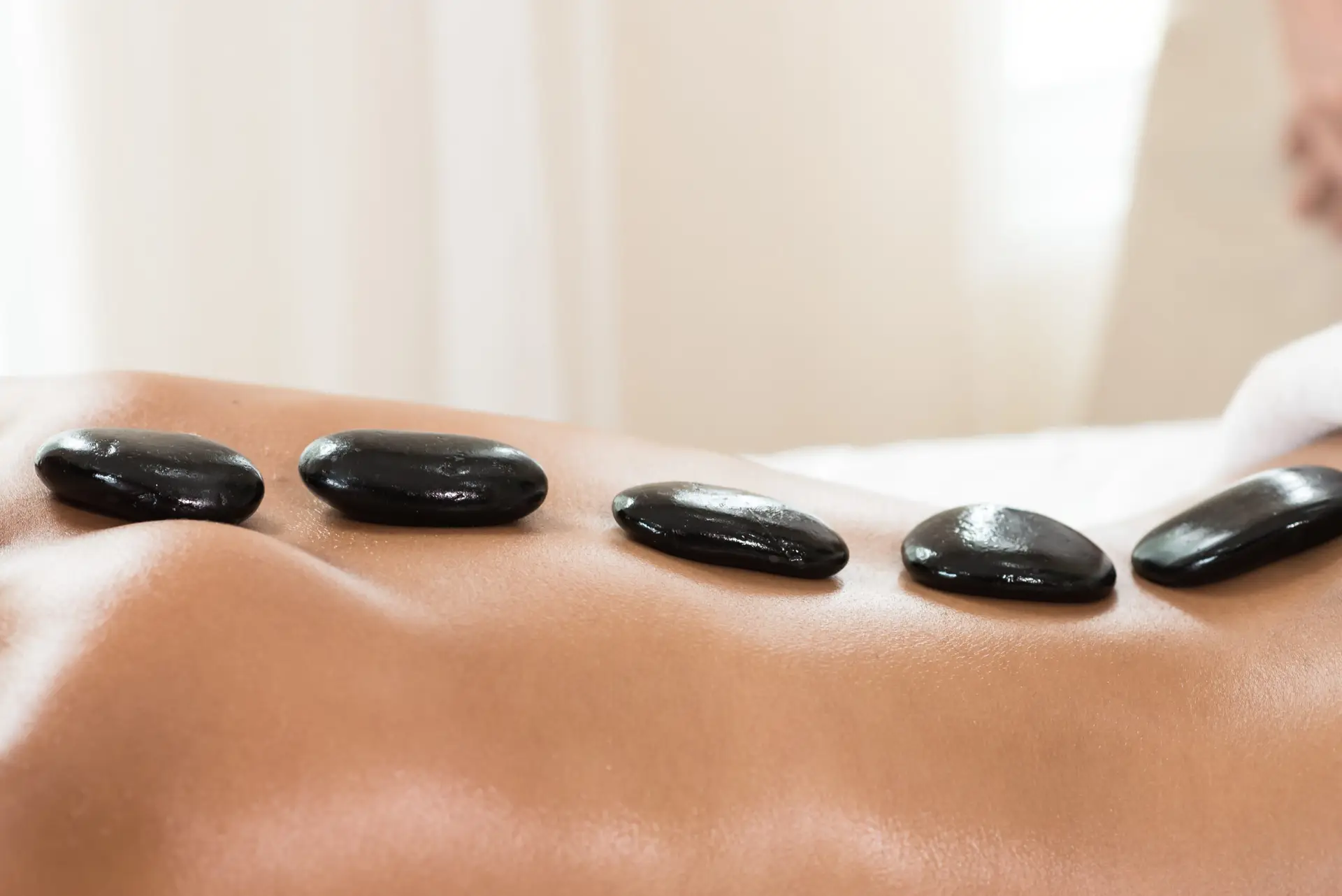 Masaż gorącymi kamieniami Warszawa – Prana Thai Spa, rozgrzane kamienie bazaltowe na ciele klientki